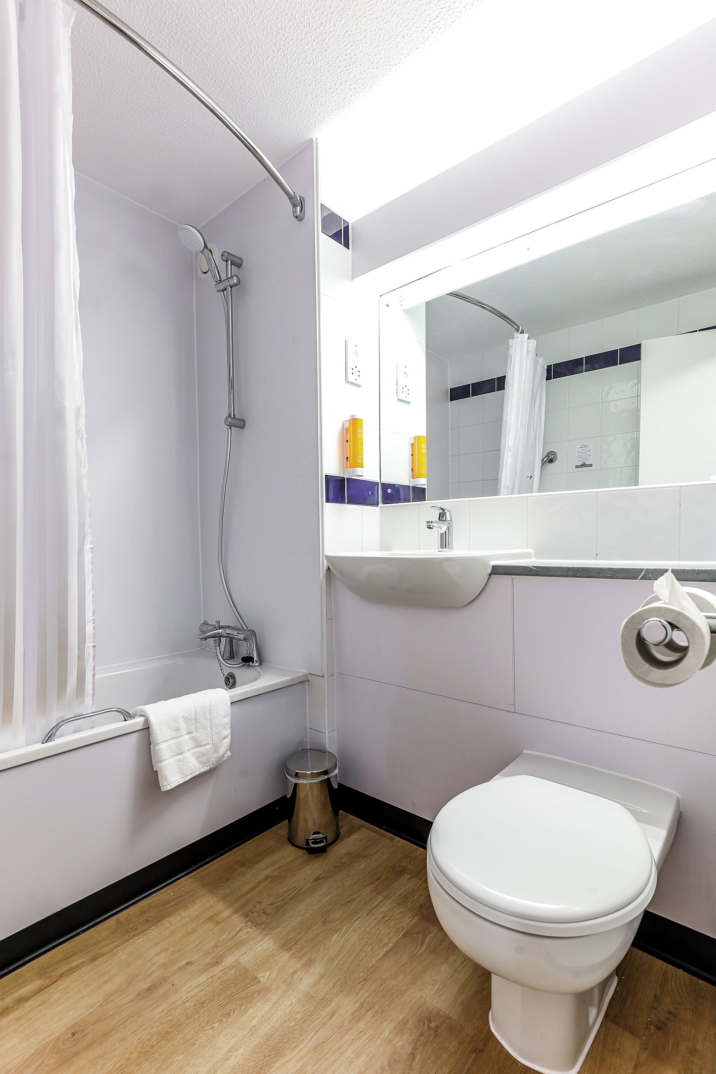 Une salle de bain équipée d’une douche, de toilettes, d’un lavabo et d’un miroir.