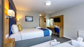 Une chambre d’hôtel avec deux lits, un bureau, une chaise, un téléviseur à écran plat et une salle de bain.