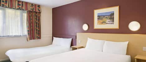 A hotel room with two single beds, a large window with curtains, a framed picture on the wall, and bedside lamps.