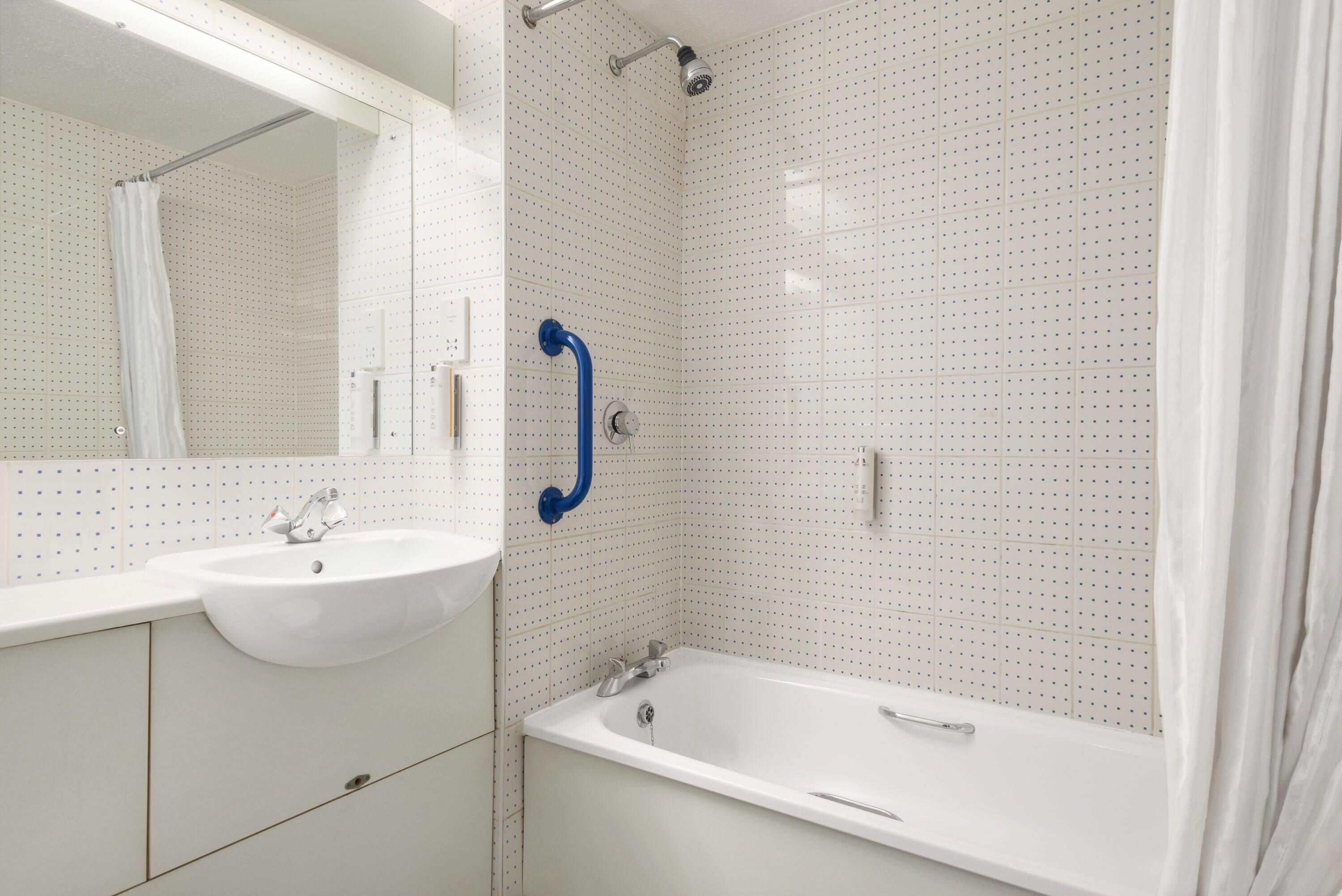 A bathroom with a white sink, a bathtub, and a shower area.