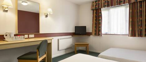 Een hotelkamer met een bed, een bureau met stoel, een televisie en een raam met gordijnen.