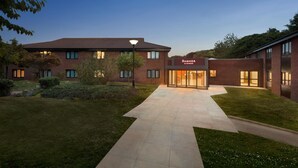 Un bâtiment moderne avec une enseigne indiquant « RAMADA » et une pelouse bien entretenue.