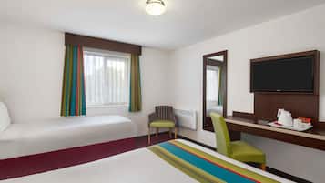 A hotel room with two beds, a desk with a flat-screen TV, a chair, and a window with curtains.