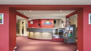 Een receptie van een Days Inn met een gebogen balie, een koelkast vol drankjes en een kaart aan de muur.
