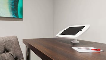 A modern office desk with a tablet, a pen, and a piece of paper.