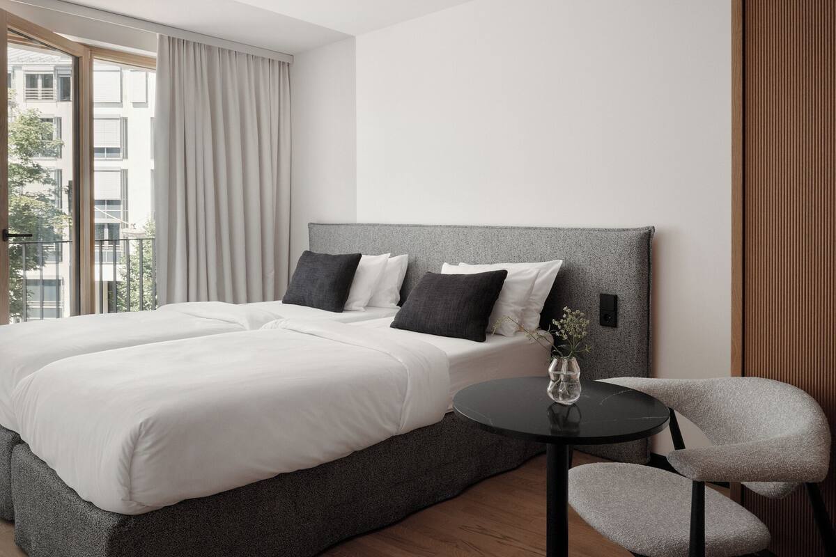 A modern hotel room with a large bed, a small table, and a chair.
