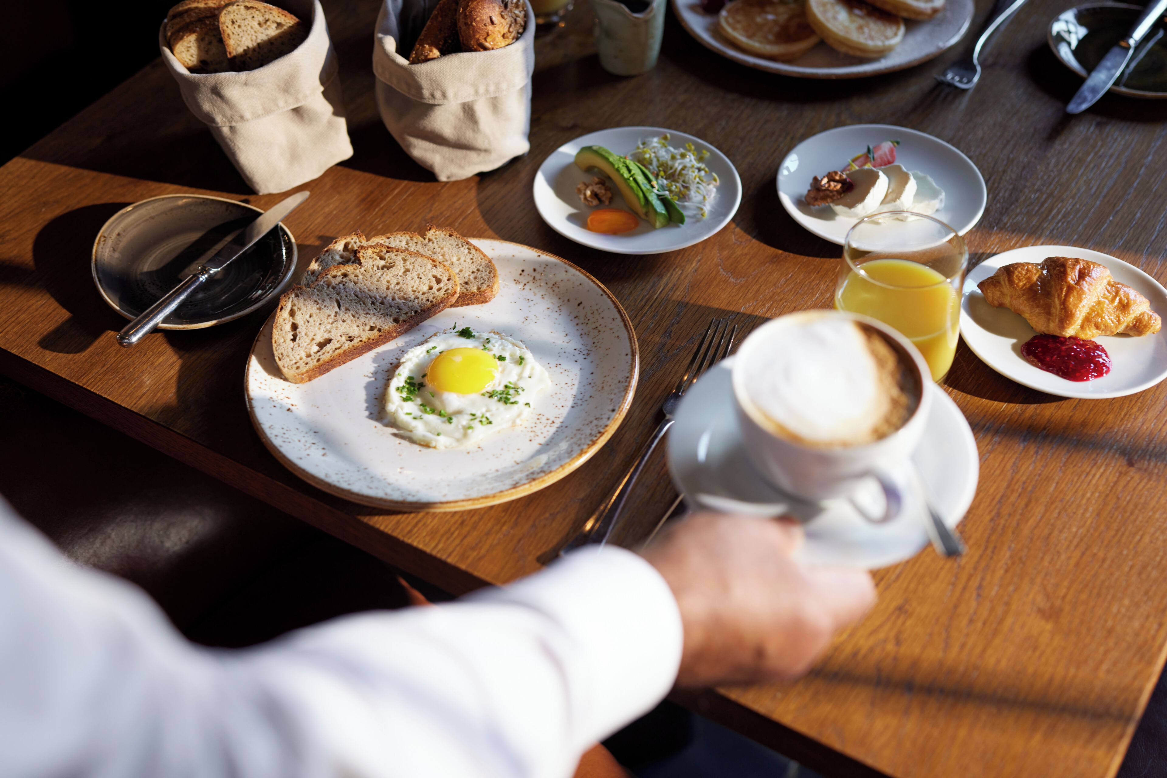 Una mesa de desayuno con diferentes platos, como tostadas, huevos y pasteles.