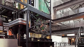 A spacious industrial interior with high ceilings, exposed ductwork, and a mezzanine level.