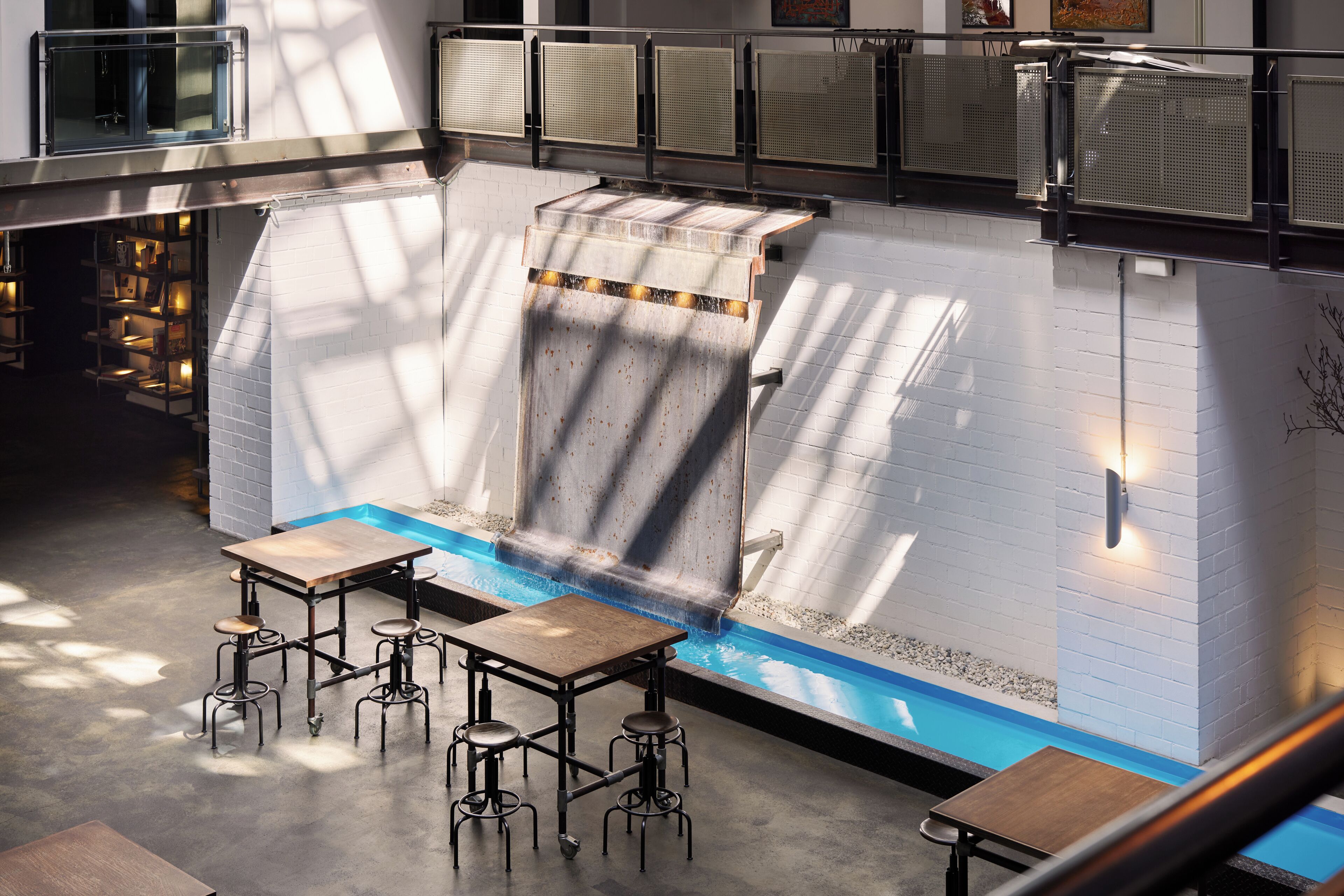 Un interior moderno con piscina, taburetes de bar y una escalera.