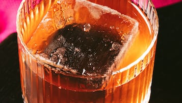 A glass with a dark liquid and ice cubes.
