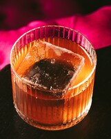 A glass with a dark liquid and ice cubes.