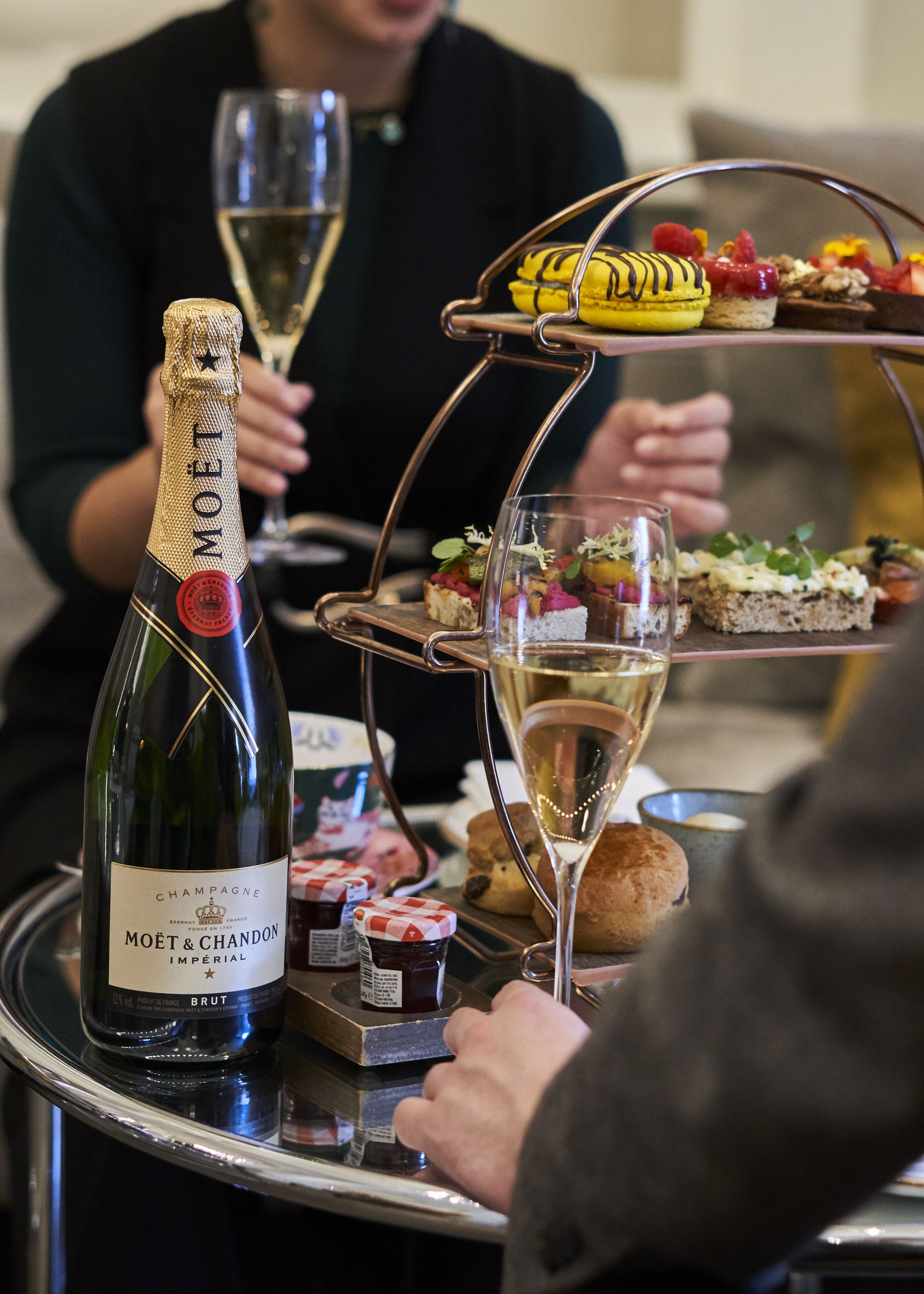 A bottle of Moët & Chandon champagne, a glass of champagne, and a tray with assorted appetizers.