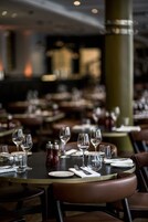 Ein Restaurant mit runden Tischen, gedeckt für das Essen, mit klaren Gläsern und Tellern.
