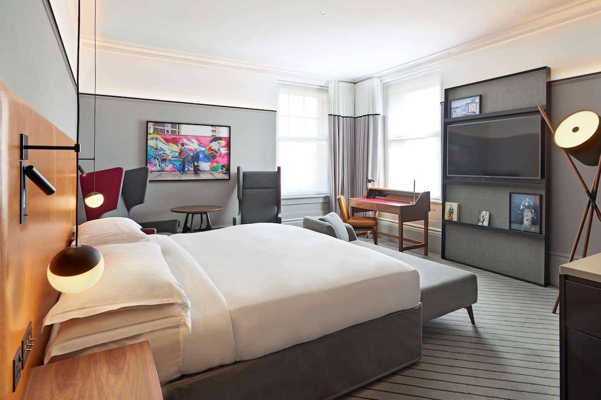 Een moderne hotelkamer met een groot bed, een bureau, een stoel en een klein tafeltje.