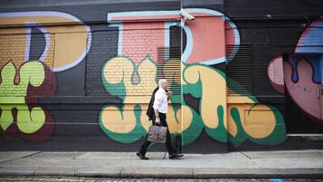 Un hombre caminando cerca de un muro con grafitis coloridos.