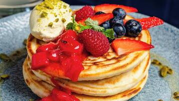 A stack of pancakes with fruit and a scoop of ice cream on a blue plate.