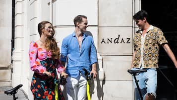 Three people standing by a building with a sign that reads "ANDAZ".