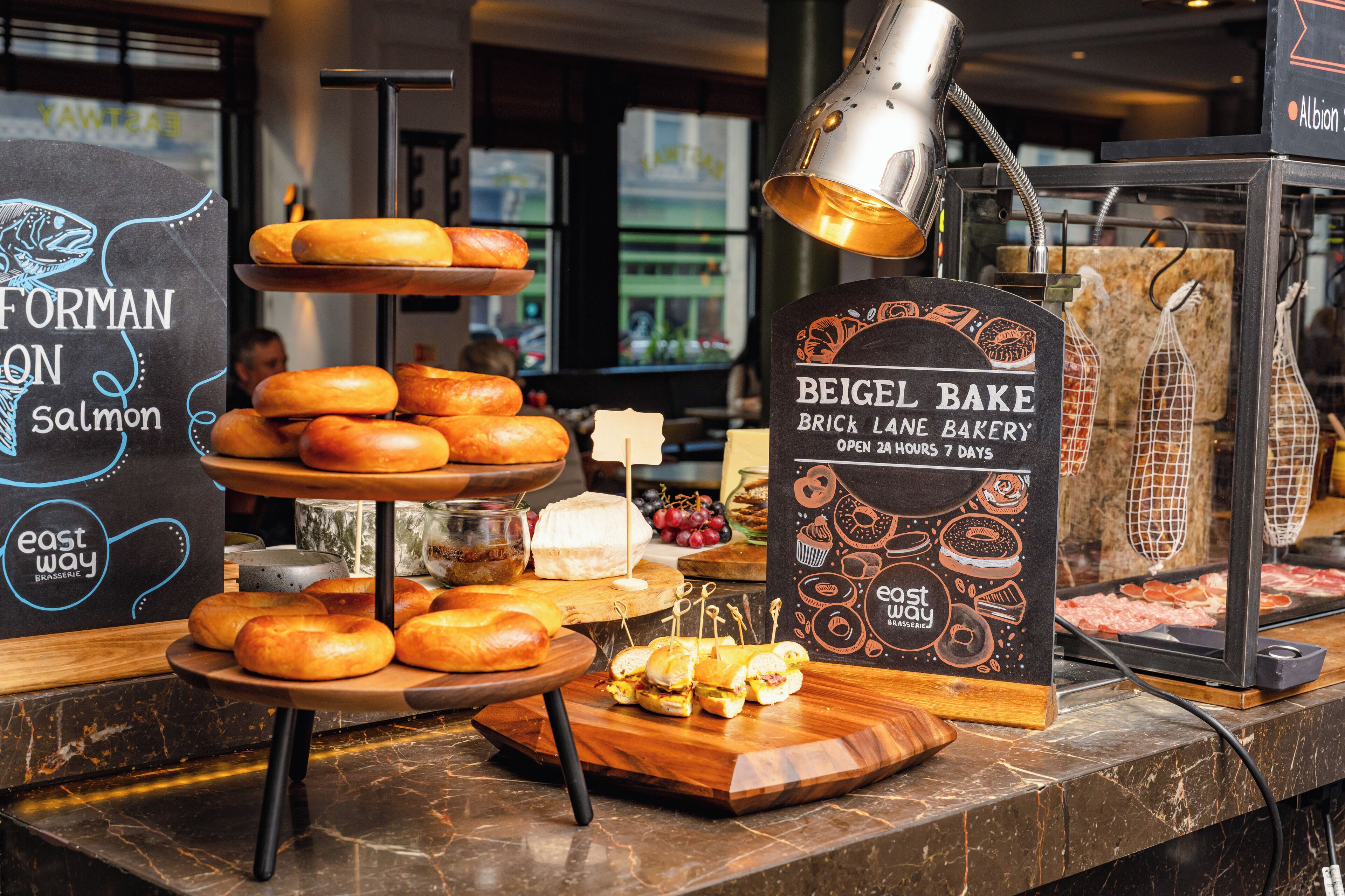 Mostrador de panadería con diversos productos horneados y un cartel que dice 'Beige Bake Brick Lane Bakery'.
