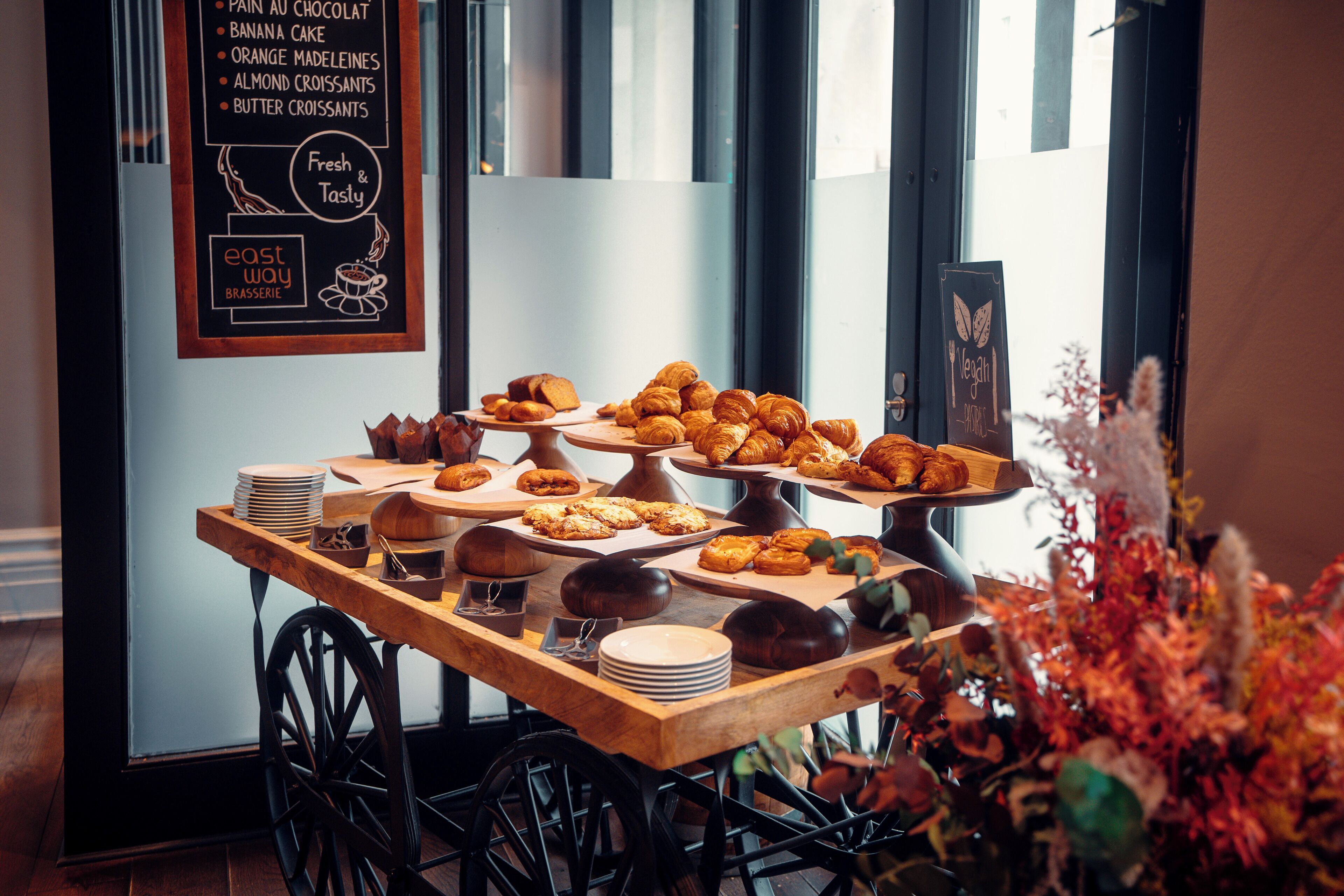 A bakery display with various pastries and a chalkboard menu listing items like chocolate cake and croissants.