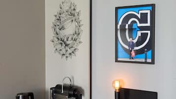 Una habitación moderna con cafetera, dos tazas, un adorno de pared y una obra de arte enmarcada con una gran 'G' en la pared.