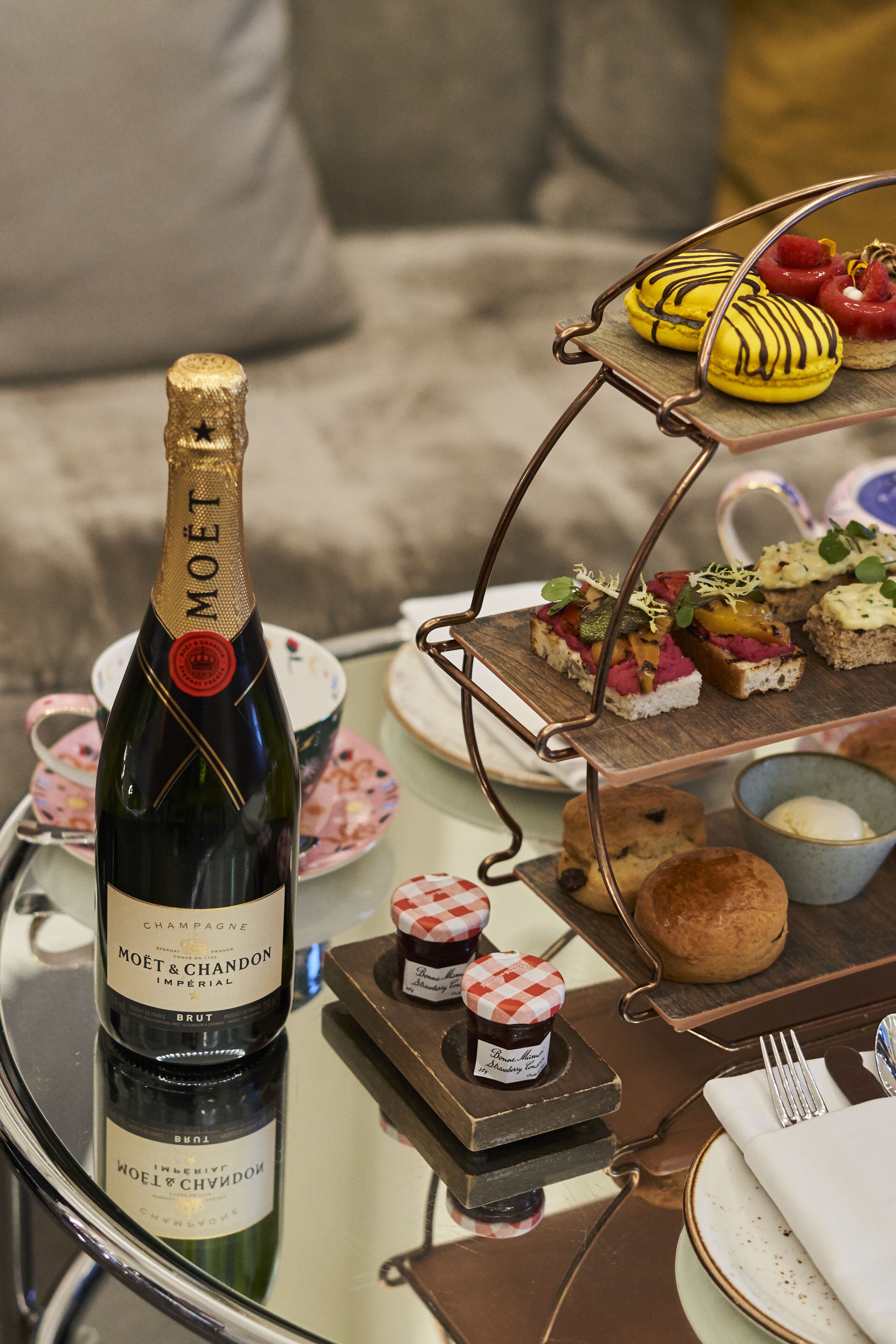 A bottle of Moët & Chandon champagne on a glass table with a dessert trolley and a small jar of jam.
