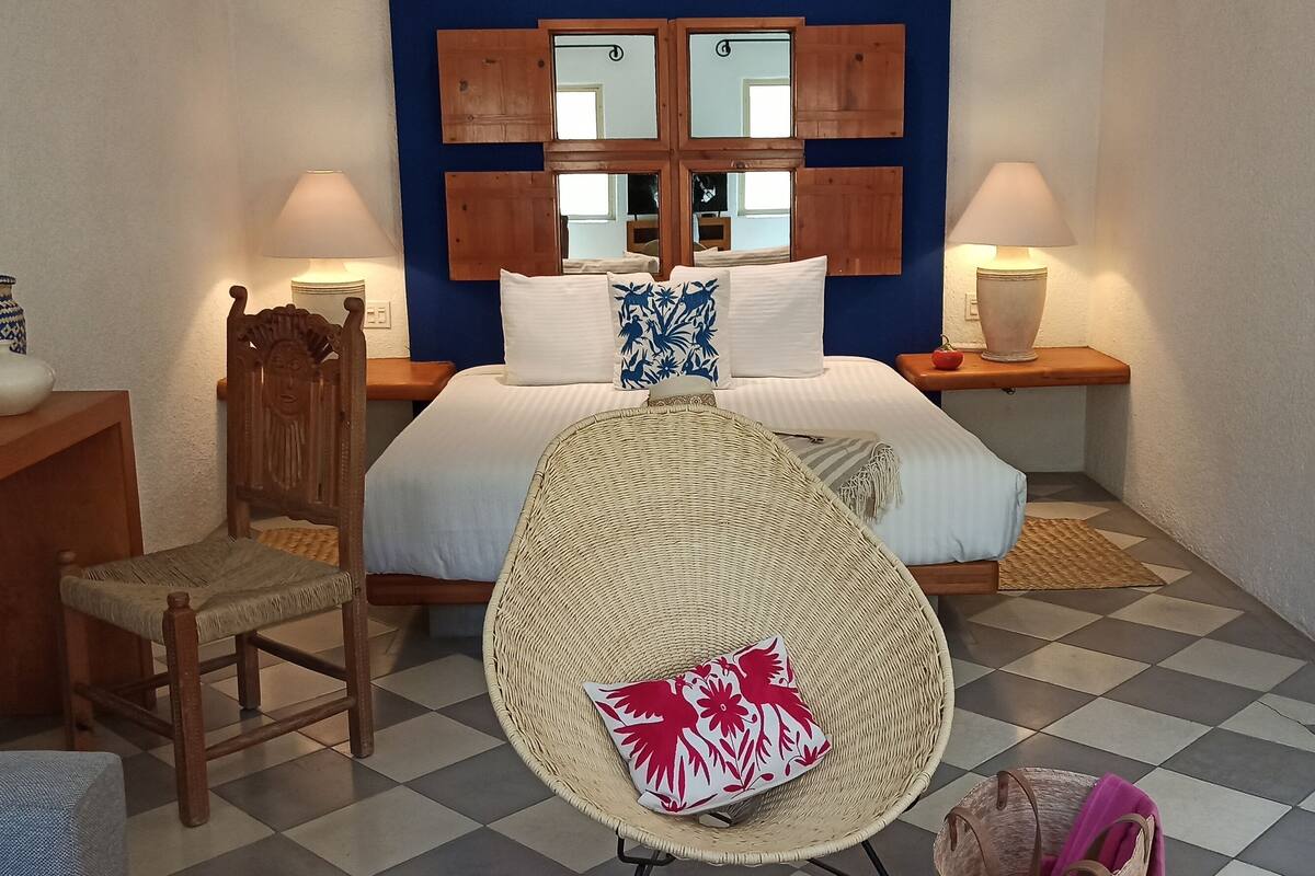 Een slaapkamer met een bed, twee nachtkastjes, een stoel, een kaptafel en een spiegel.