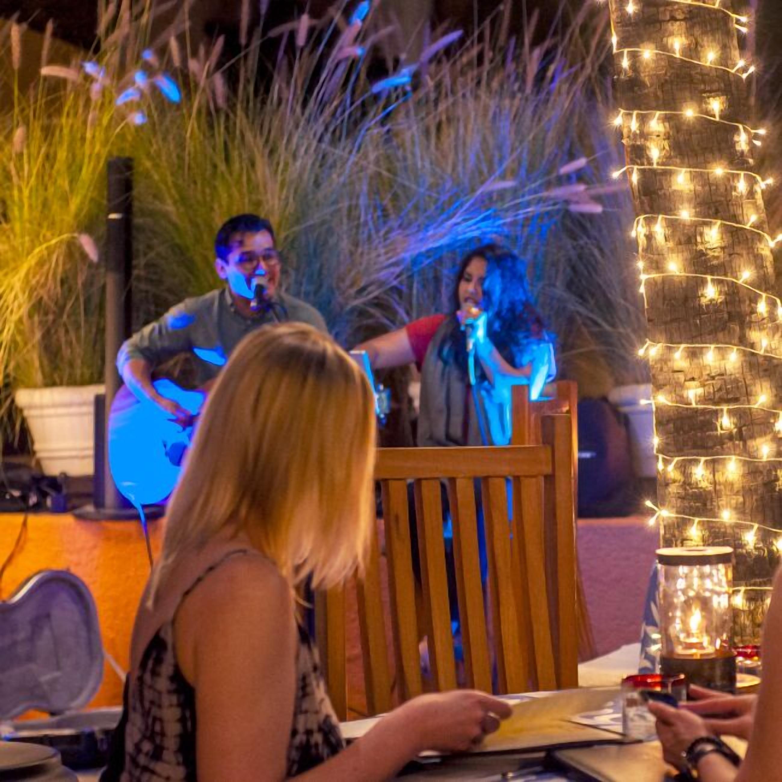 An outdoor dining area with string lights, a wooden table, and chairs.