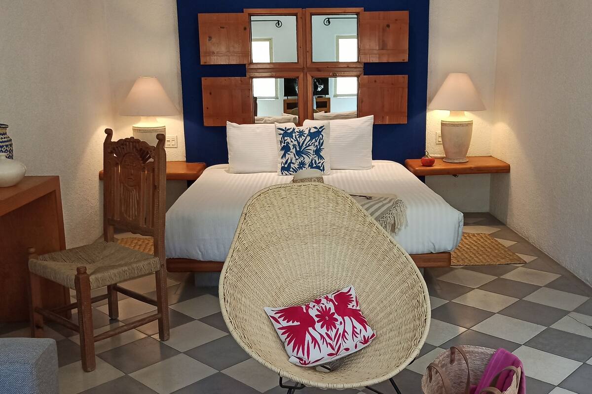 Een slaapkamer met een bed, twee nachtkastjes, een stoel, een dressoir en een spiegel.