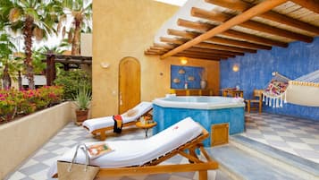 Uma área de spa com duas espreguiçadeiras, uma banheira de hidromassagem e um balanço.