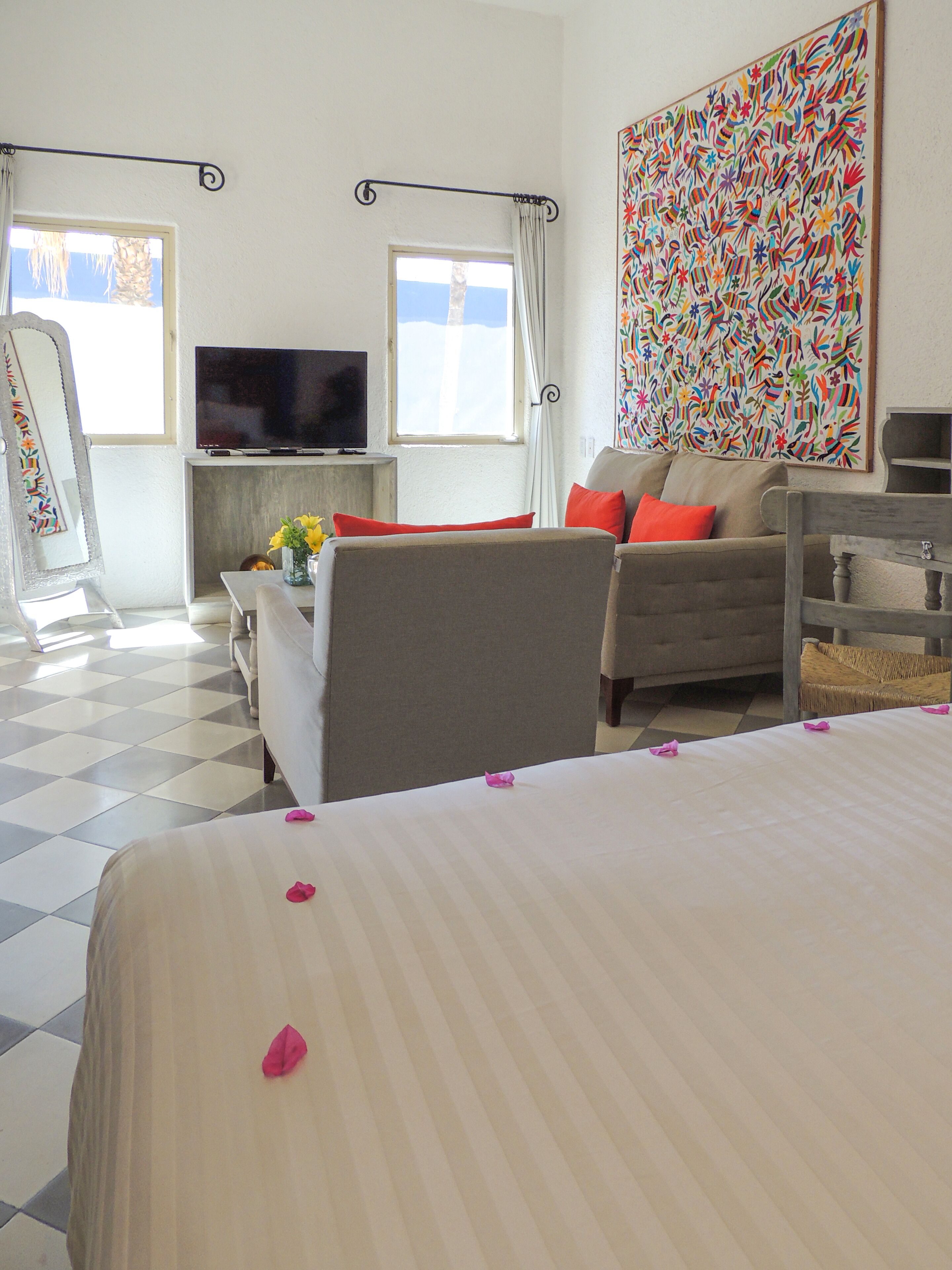 Hotelkamer met een bed, een bank, een televisie, een schilderij en een raam met gordijnen.