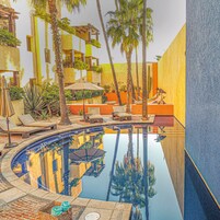 Una piscina al aire libre, sombrillas, sillones reclinables de piscina