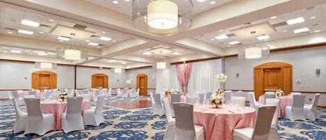 A large conference room with round tables and chairs, a patterned carpet, and a high ceiling with recessed lighting.