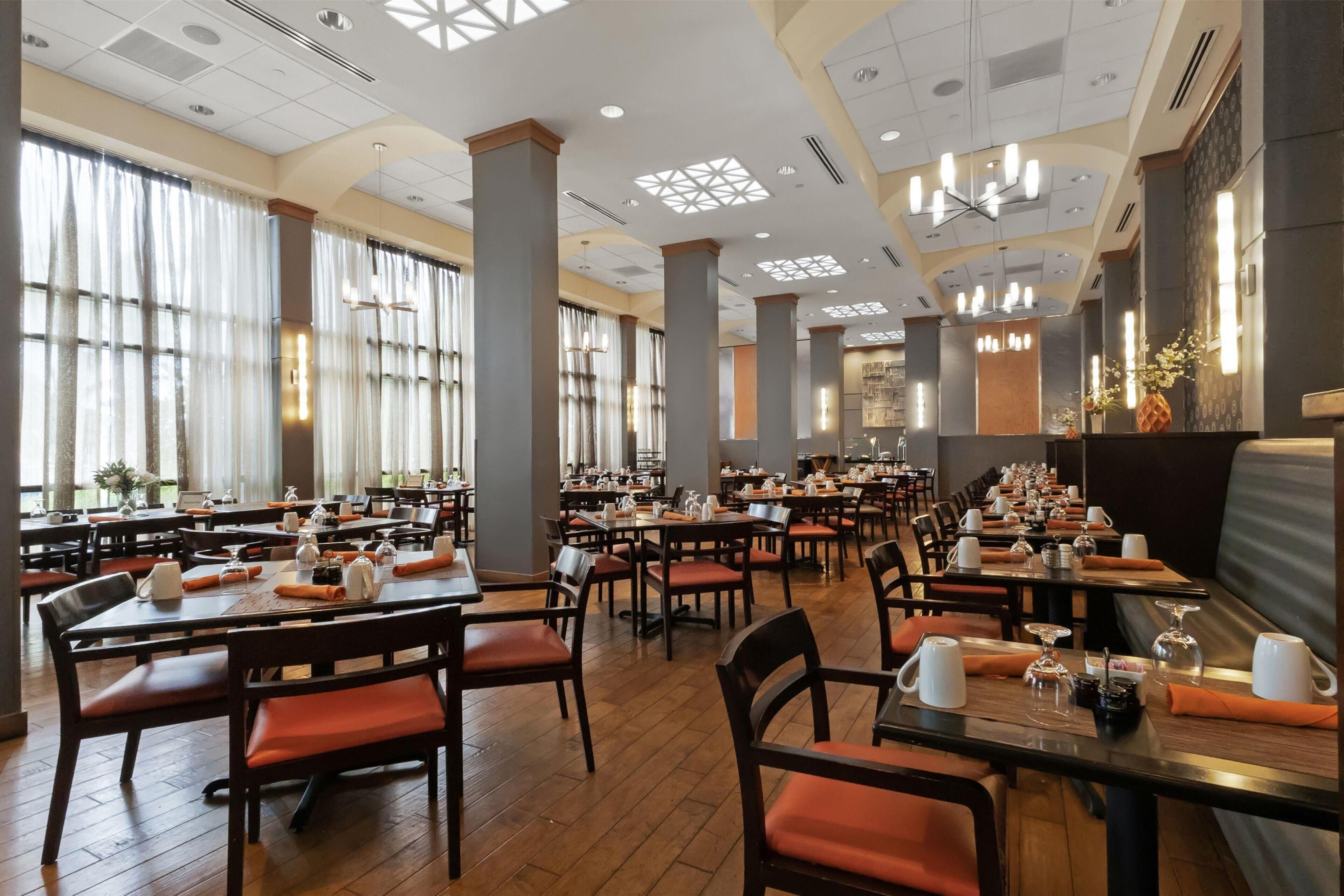 A spacious restaurant with high ceilings, large windows, and multiple dining areas.