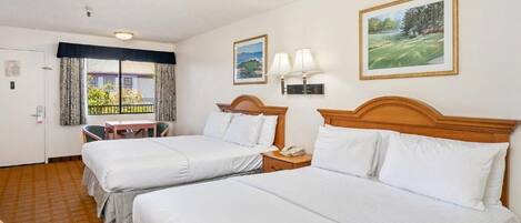 Une chambre d’hôtel avec deux lits, une petite table, une chaise et une fenêtre avec des rideaux.