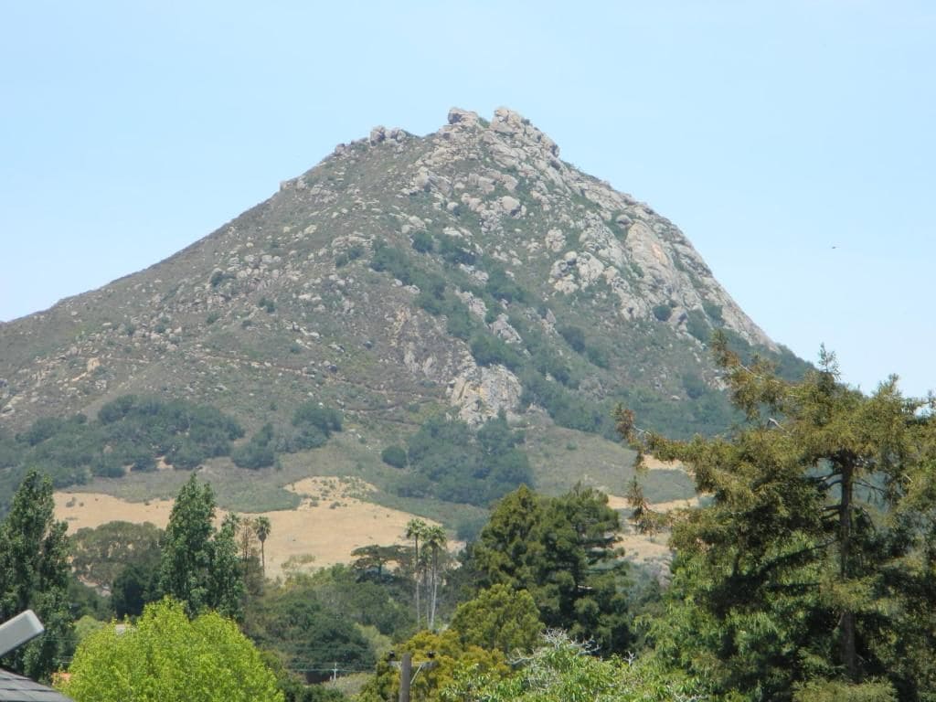A mountain with rocky terrain and sparse vegetation.