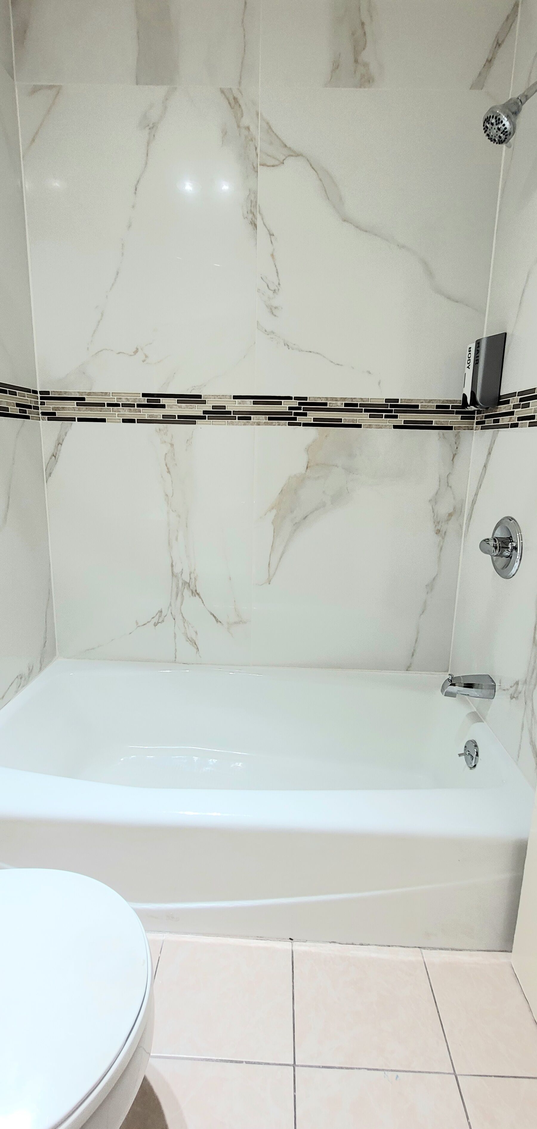 A bathroom with a marble bathtub, a showerhead, and a toilet.