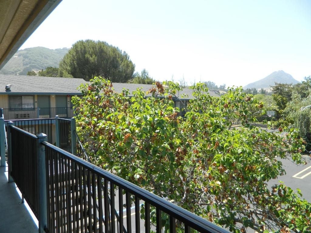 A balcony with a view of a parking lot and a mountain in the distance.