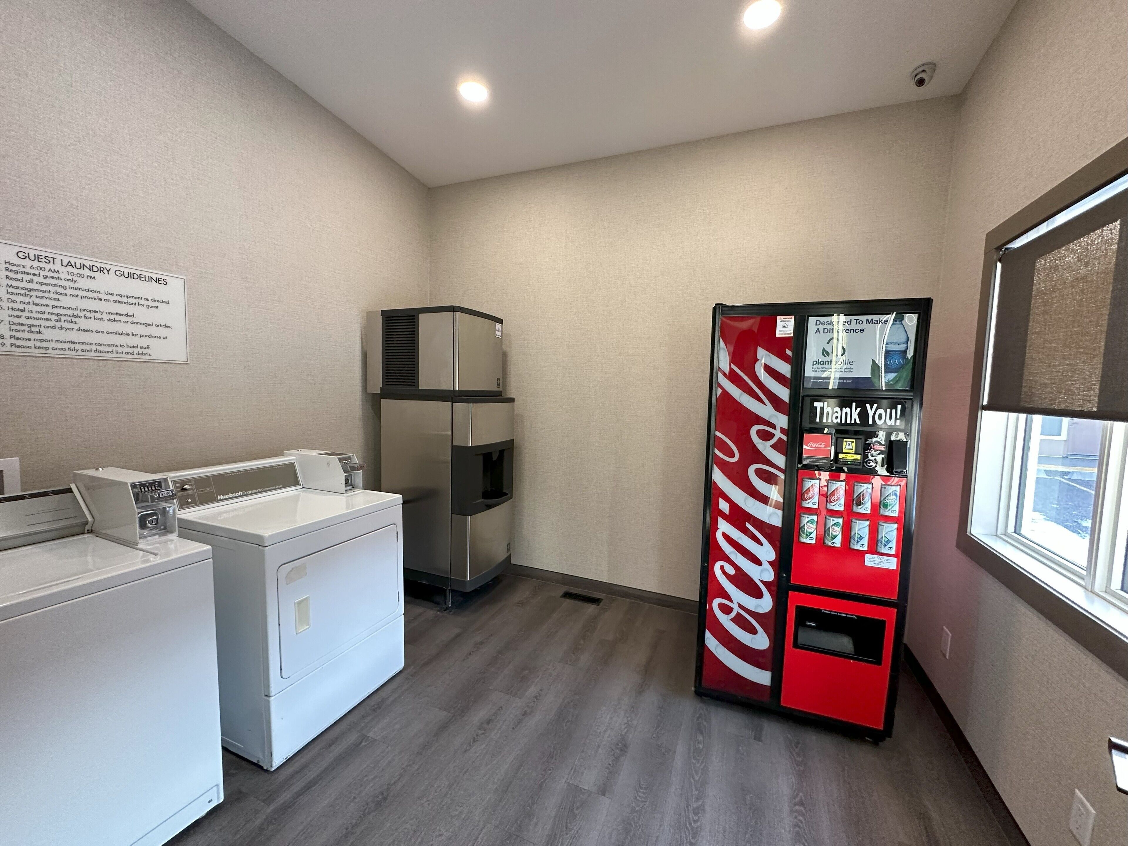 Habitación de hotel con área de lavandería, máquina expendedora y ventana.