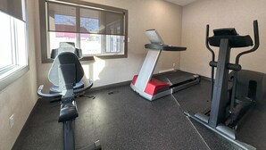 A gym with a treadmill, elliptical, and weight machine.