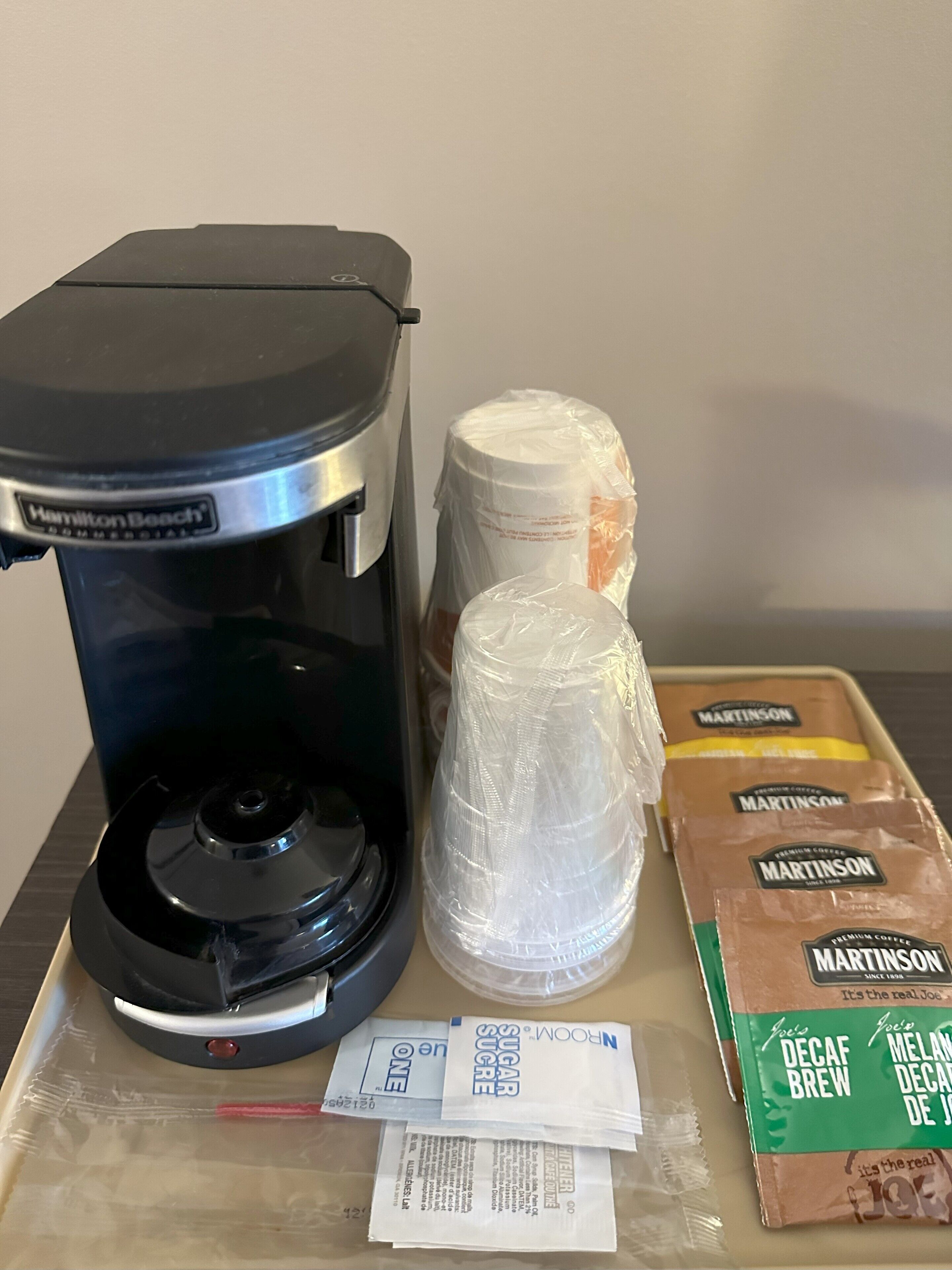 Une machine à café, deux paquets de café emballés et une dosette de café sur une table.