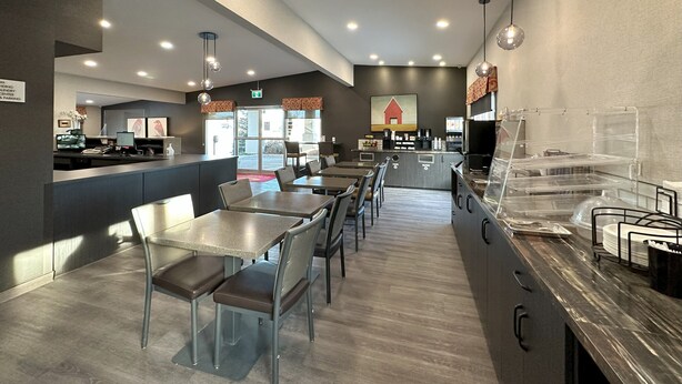 A modern restaurant interior with a long counter, multiple tables, and chairs.