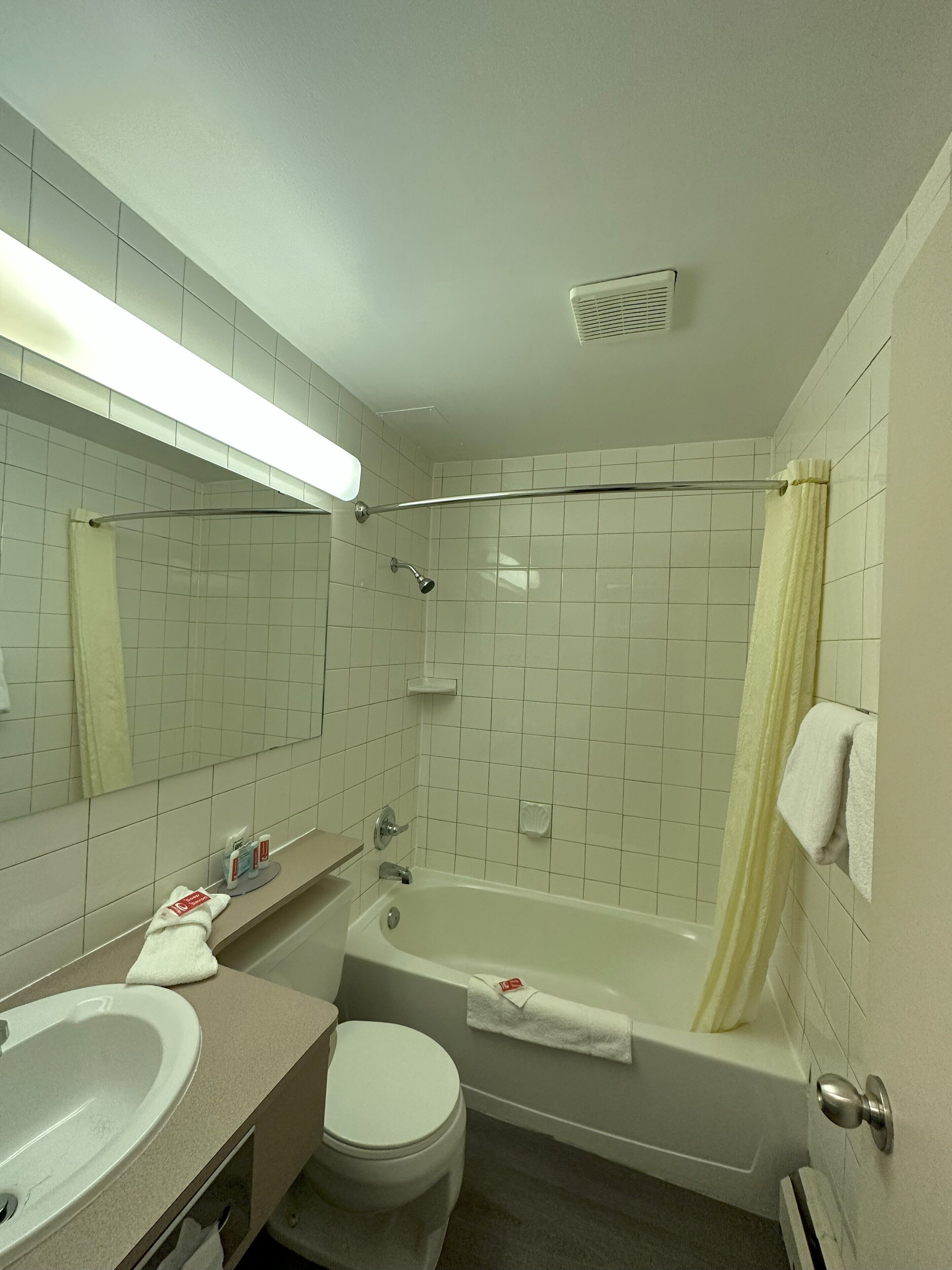 A bathroom with a bathtub, toilet, sink, and a mirror.