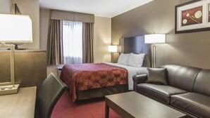 A hotel room with a bed, a leather sofa, a desk, and a TV.