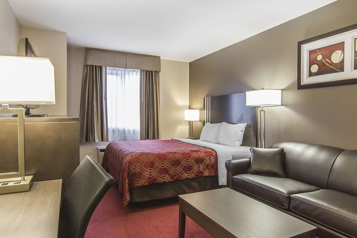 Hotellihuone, jossa on sänky, nahkasohva, työpöytä ja televisio.