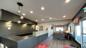 A hotel reception area with a modern design, including a reception desk, seating area, and large windows.