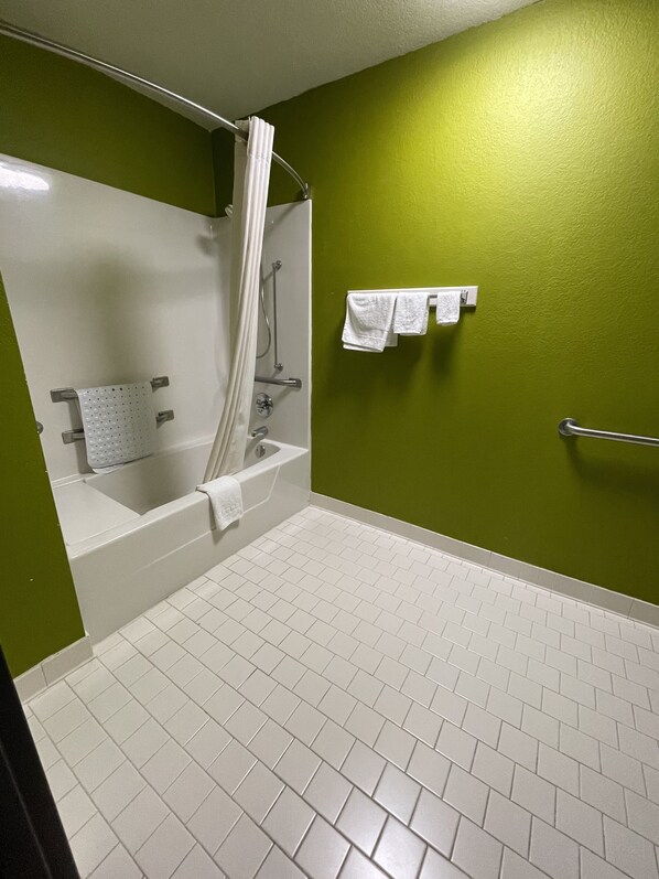 A bathroom with a bathtub, shower, and a green wall. - Relax Inn (McRae-Helena)