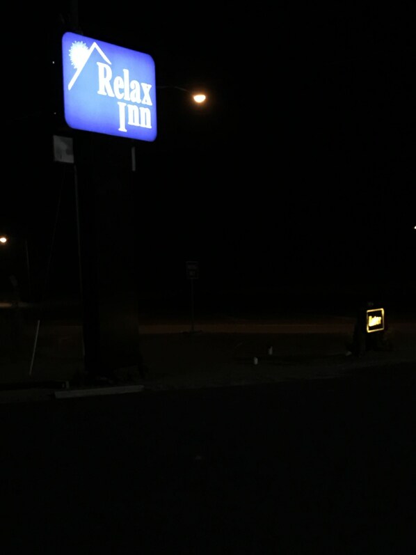 A Relax Inn sign illuminated in blue against a dark night sky.