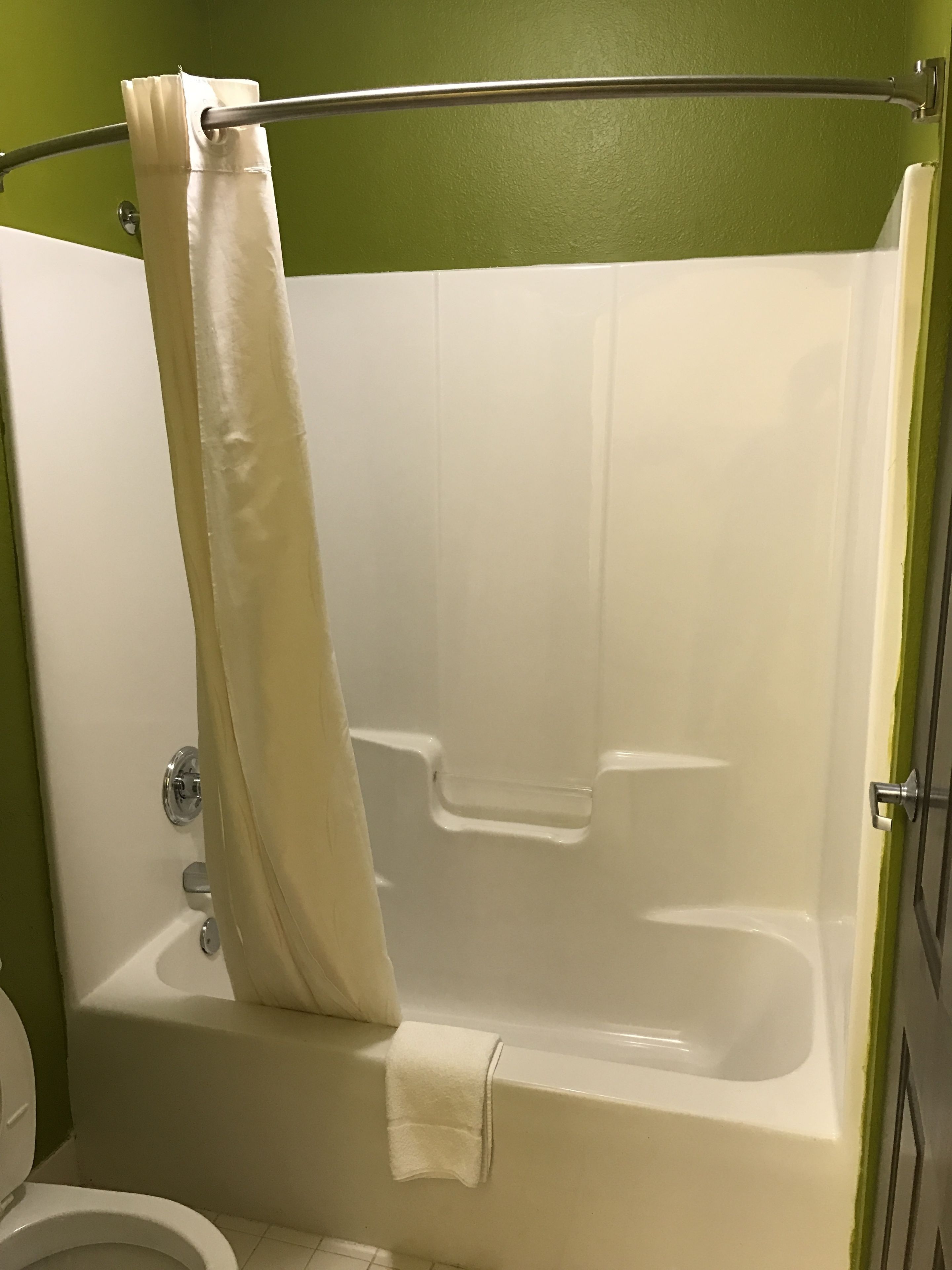 A bathroom with a bathtub, a shower curtain, and a toilet.