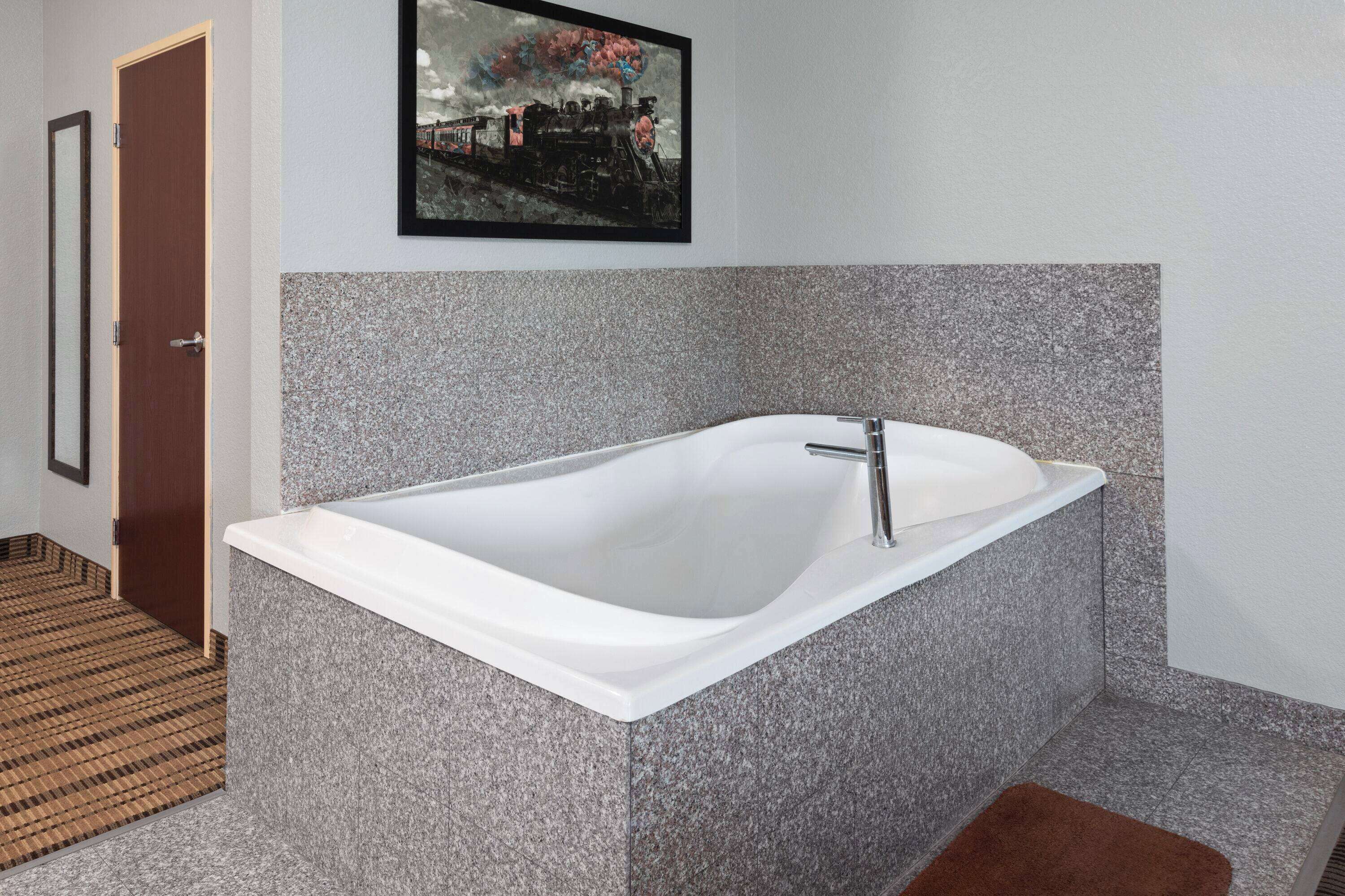 Un baño moderno con una bañera independiente, un cuadro enmarcado en la pared y un suelo con diseño.