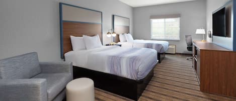A hotel room with two beds, a sofa, a desk, and a TV.